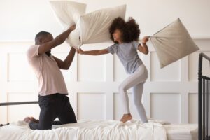 Dad and child in new bedroom playing with pillows