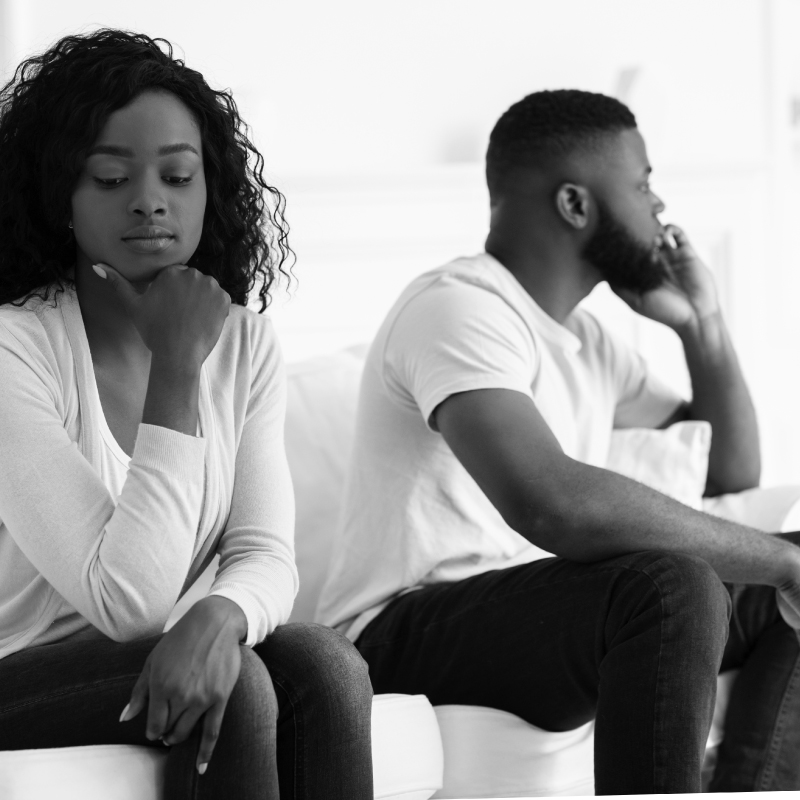 a couple sit on a couch both facing the opposite way in disagreement